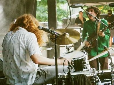 Finn Wolfhard is singing while playing guitar in the picture.